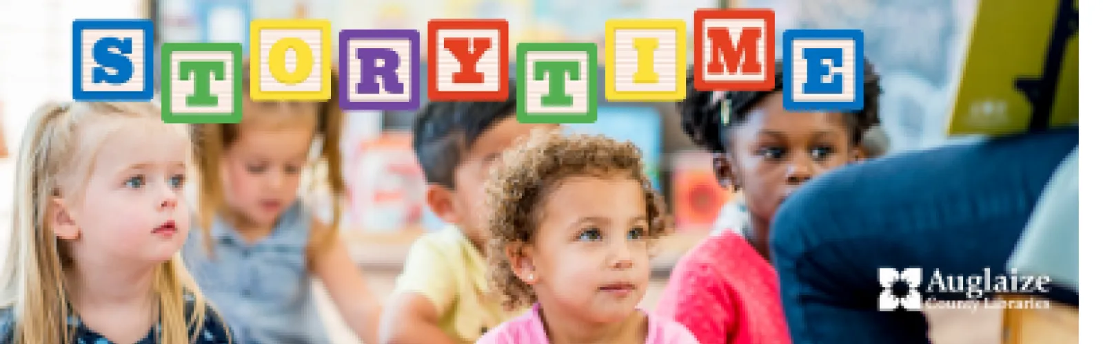 children sitting on ground facing a teacher while she reads a book to them; text reads "Storytime" in children's block letters